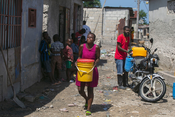 아이티의 포르토프랭스에 사는 한 여성이 지역 상인으로부터 구입한 물을 운반하고 있다. [사진출처(Photo source) = 유엔뉴스(UN News) / UNICEF]